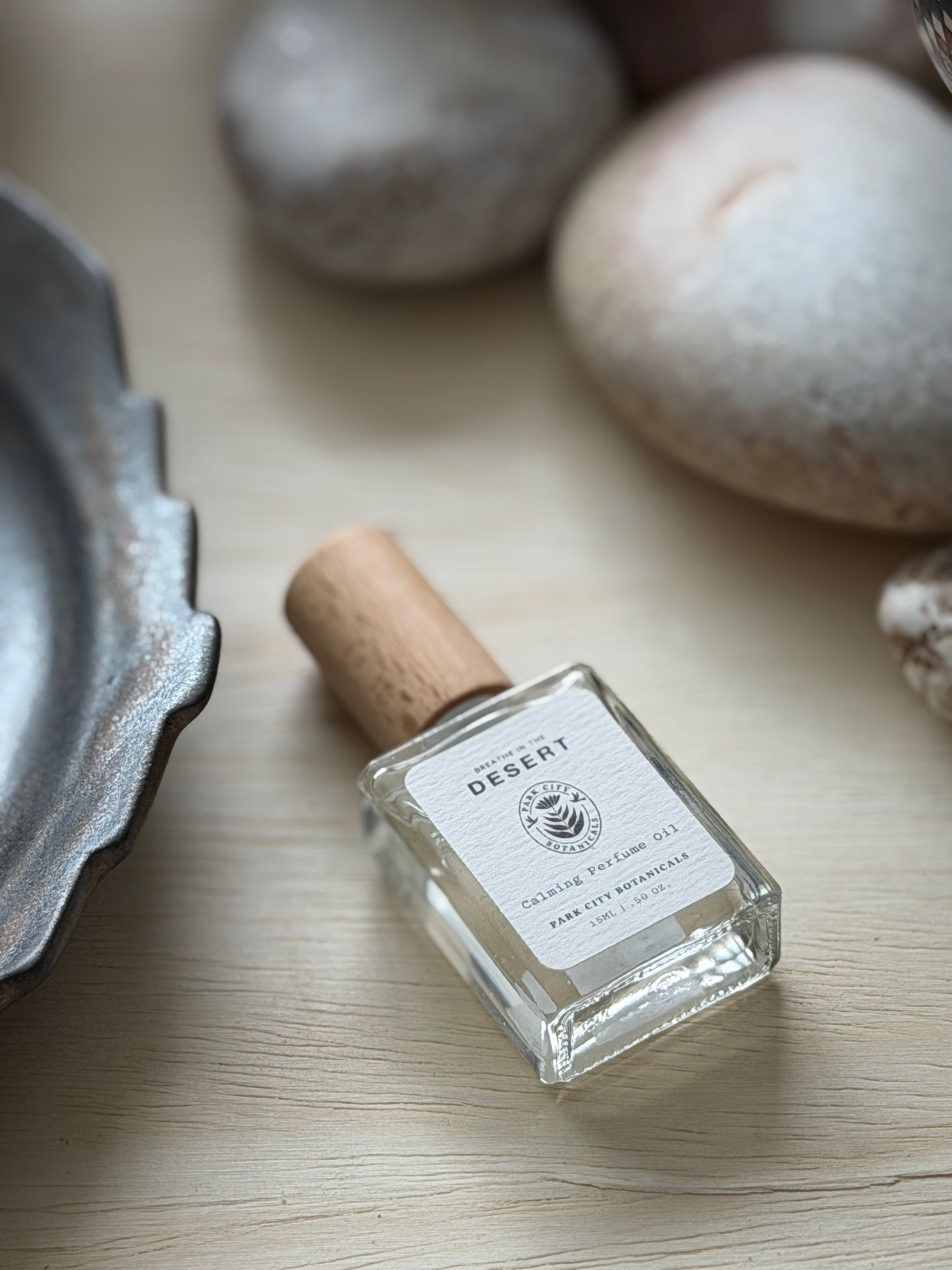 Small bottle with cork lid on a wooden surface with stones and a metal object in the background