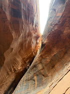Person climbing through a narrow rock crevice in a desert landscape