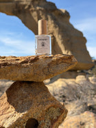 Bottle of Desert Rose perfume on a rock with clear blue sky