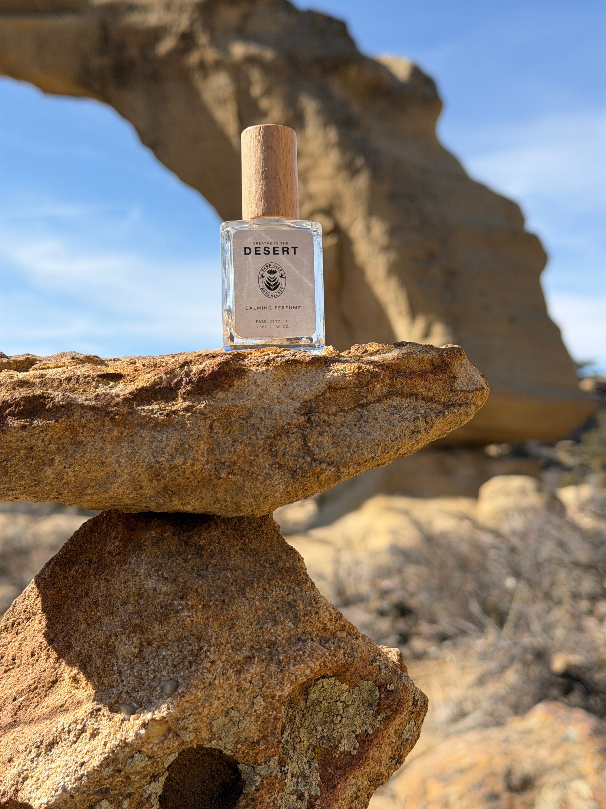 Bottle of Desert Rose perfume on a rock with clear blue sky