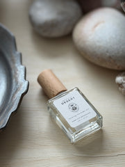 Small bottle with cork lid on a wooden surface with stones and a metal object in the background