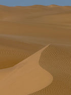 Desert landscape with sand dunes under a clear blue sky