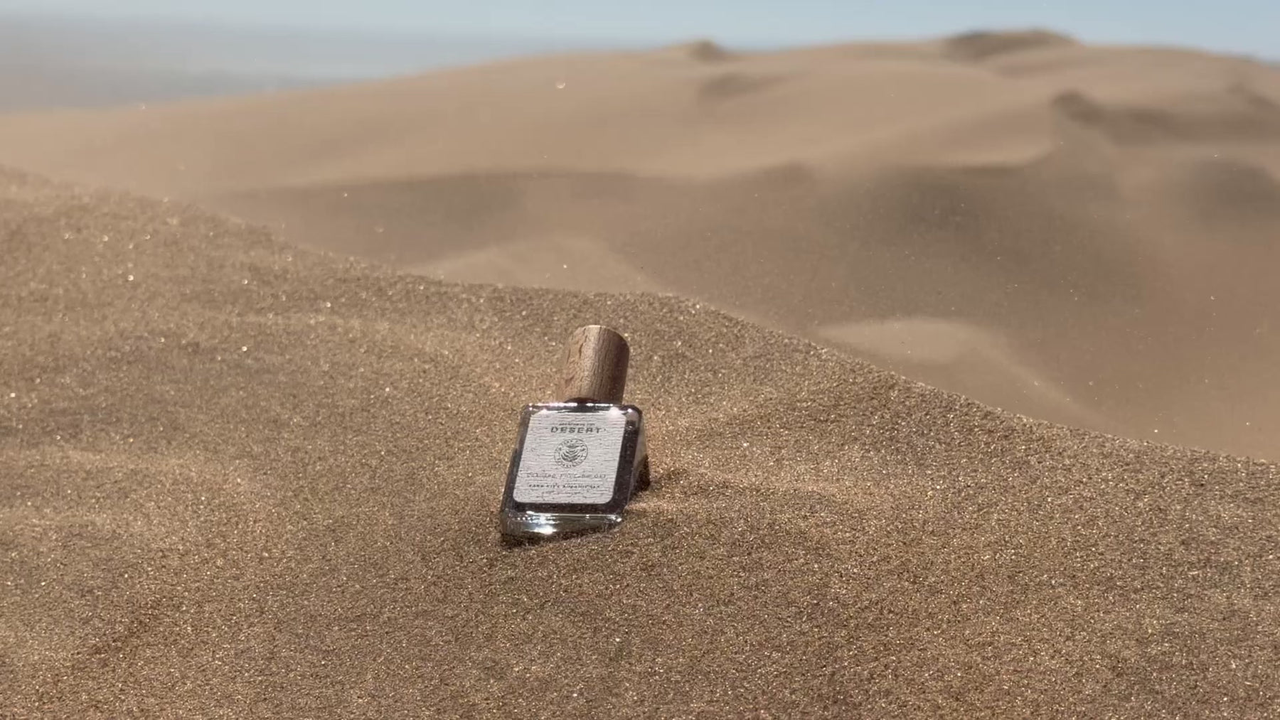 Bottle of Park City Botanicals perfume in the desert sand